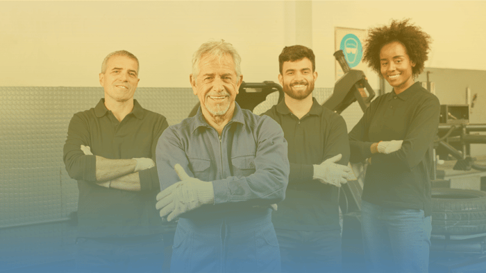 group of four auto repair shop employees standing shoulder to shoulder with their arms crossed