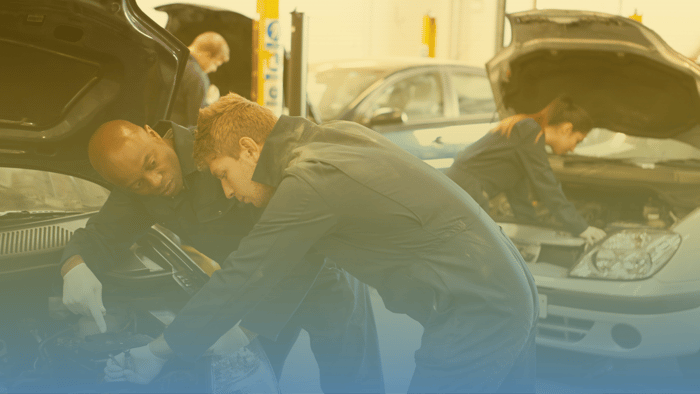 two technicians standing over an open hood of a vehicle