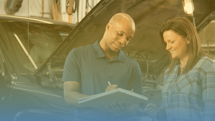 service advisor writing on clipboard and talking to vehicle owner