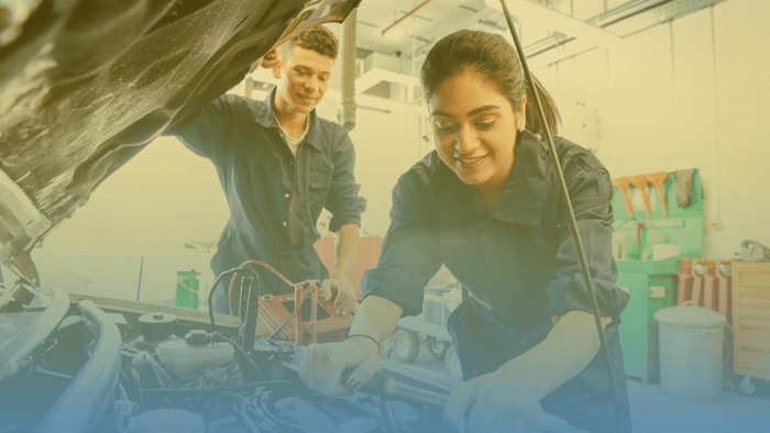 two technicians working under the hood of a car 