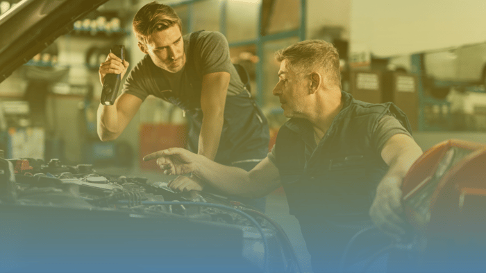 two technicians working on a car under the hood