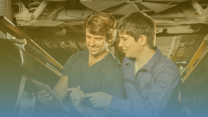 two technicians in a shop looking at a tablet